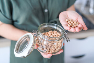 A close-up of chickpeas in a woman s hands this product helps lower cholesterol and maintains...