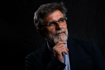 Portrait of handsome man in a studio on a dark background. Handsome man posing. Middle-aged good...