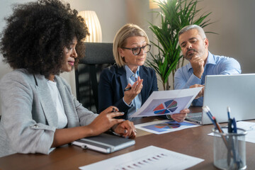 Three busy happy middle aged professional business man and two women executive leaders team using...
