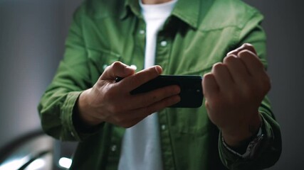 A football fan watches a match on his phone and rejoices at the victory and a goal scored.
A man is emotionally holding a mobile phone in his hands.
Sports, online, eSports, gambler, excitement