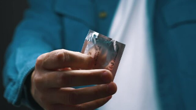 The man in front of the camera holds a condom.
Method of contraception and protection against unwanted pregnancy.
The problem of sexually transmitted diseases and sexual illiteracy