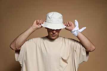 Fashionable portrait of handsome man in stylish outfit on brown background