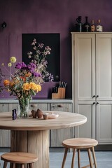 A beautifully arranged modern kitchen featuring a round wooden table. vibrant purple walls adorned with floral art. and elegant kitchenware. creating a cozy ambiance for culinary activities