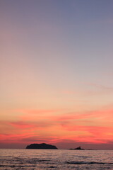 sunset with vivid pink and orange clouds over a calm sea. Two islands silhouette the horizon, creating a dreamy and romantic atmosphere perfect for travel, nature, and relaxation themes.