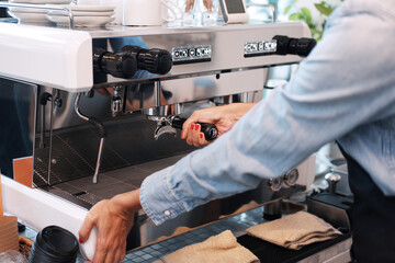 Close up on hand of professional Caucasian barista woman prepares coffee with coffee maker machine in cafe
