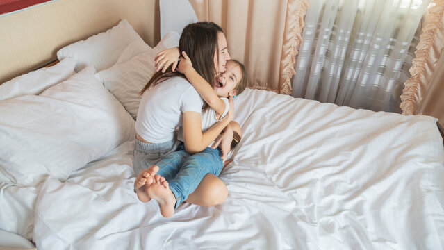 Mother and her daughter the girl play and hug in the bedroom in the morning
