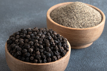 Ground black pepper with grains of black pepper on gray background