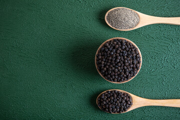 Ground black pepper with grains of black pepper on green background