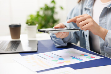 Woman taking photo of document using scanning app on smartphone at desk in office, closeup. Space for text
