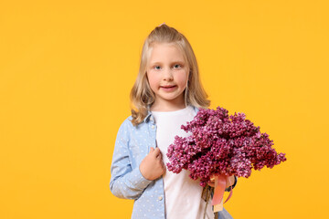 Little girl with bouquet of lilac flowers on yellow background