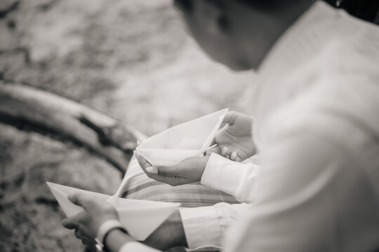 Close up of couple holding paper boats together in black and white, symbolizing dreams, connection, and shared journeys in a tender and nostalgic moment