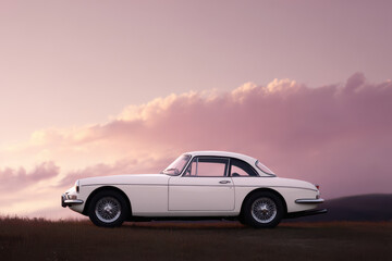 Obraz premium classic retro racing car parked under stunning evening sky featuring soft hues and minimalist composition