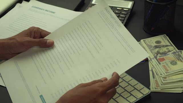 A businessman is reviewing a sales report and entering the data into a computer system. This footage conveys the idea of a person engaged in business and financial activities.