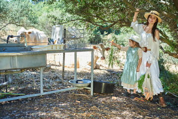 young mother and her daughter in dresses on a farm on a summer day