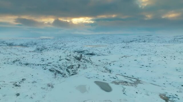 Winter drone view of frozen lake and surrounding snowy tundra at Musta - Tunturi Ridge, part of the remote Kola Peninsula in Arctic Russia.