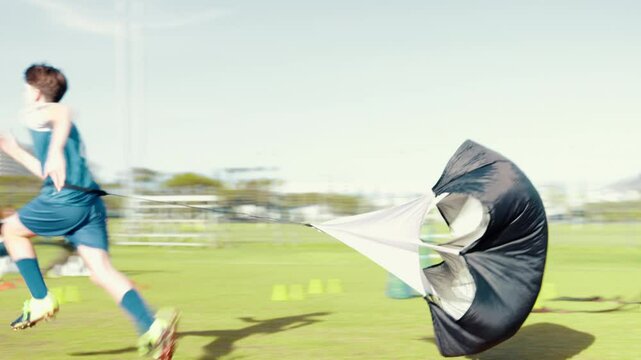 Kid, running and parachute for sports practice on field, strength training and fitness exercise. Child, drill equipment and game workout for endurance, speed challenge and cardio for learning skills