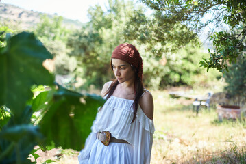portrait of young woman with dark hair in white dress on farm in summer