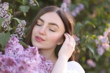 Fototapeta premium Beautiful woman among lilac flowers and leaves outdoors, closeup
