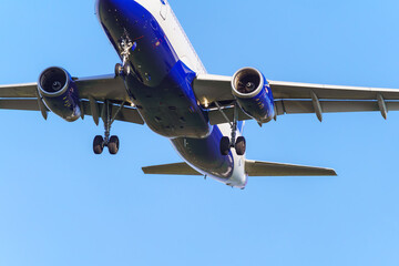 Close-up of an approaching passenger airplane preparing to land. Clear sky in the background.