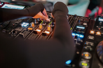 A DJ sets up a professional audio mixer surrounded by glowing buttons and displays, conveying the...