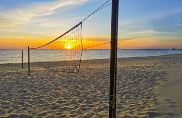 Sonnenaufgang am Strand von Zinnowitz auf Usedom, fotografiert durch ein Volleyballnetz. Im Hintergrund die Seebrücke und der goldene Horizont über der Ostsee. Symbolisches Bild für Ruhe, Perspektive 