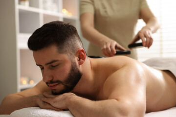 Obraz premium Man receiving relaxing massage with stones in spa salon