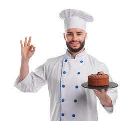 Happy confectioner in uniform holding delicious chocolate cake and showing ok gesture on white background