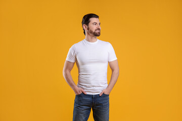 Fototapeta premium Man wearing blank white t-shirt on orange background. Mockup for design