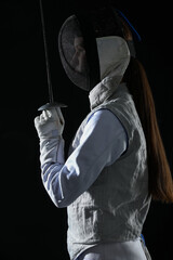 Fencer with epee on black background. Combat sport