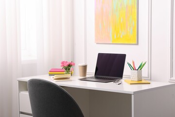 Workplace with laptop and beautiful flowers in office. Space for text