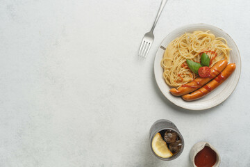 Delicious spaghetti and sausages with tomato garnish on minimalist table setting