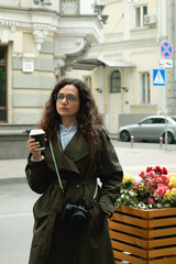Trendy woman photographer enjoying coffee to go outside