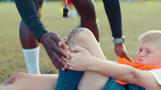Soccer field, coach and child with knee pain for injury, bone dislocation and muscle tension in sports. Pitch, hands and football player with ache for patellar tendinitis, accident or mentor for help