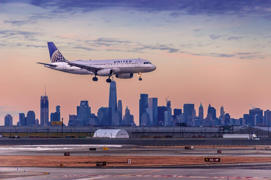 United Airlines airplane landing at New York City Newark airport backdrop lower Manhattan evening city skyline