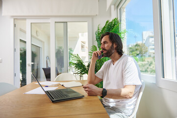 Remote Work in Bright Minimalist Home Office with Relaxed Professional Man