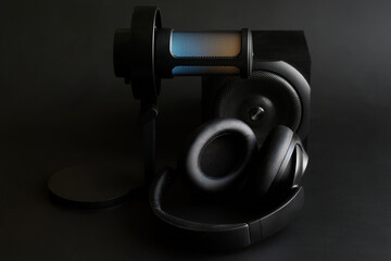 Wide-angle shot of an LED-illuminated microphone, speaker and headphones on a black surface, perfect for podcast and live stream branding. Photo