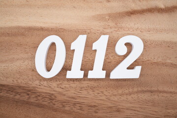 The numbers are made of white painted wood placed on a brown wooden floor.