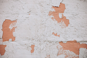Old plaster wall with peeling paint and wear marks in a residential area