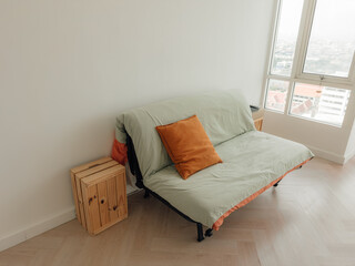 Green sofa bed with brown pillow in cozy living apartment.