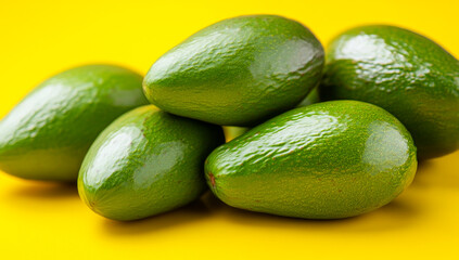 Green avocados on yellow BG. Six ripe green avocados are beautifully arranged on a vibrant yellow background, highlighting their smooth texture.