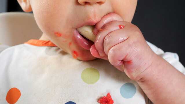 Slow motion clip of a baby eating a piece of pear, baby led weaning method