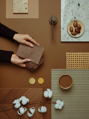 Warm-toned material mood board with natural textures, cotton branches, and fabric samples for interior design inspiration.