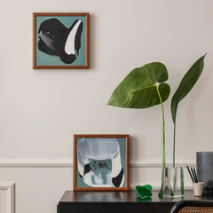 Modern composition of workplace interior with mock up poster frame, black desk, rattan chair, stylish vase with leaves, colorful sculpture, stucco on wall and personal accessories. Home decor Template