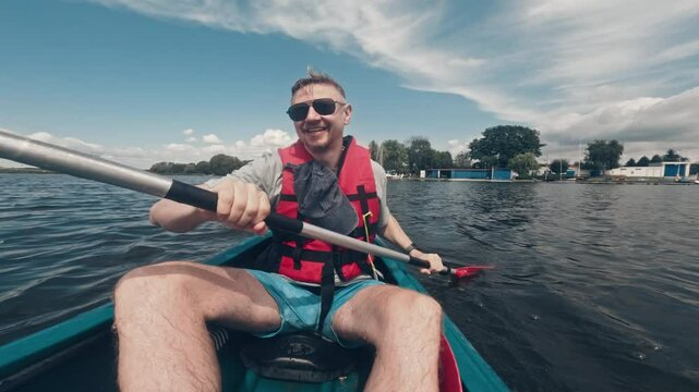 Smiling Man Joyfully Paddles A Canoe On A River During A Happy Family Weekend