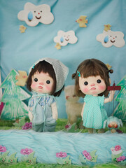 Cute dolls. Two adorable girl dressed in green color and jeans outfit. Vintage dolls are on display at the doll weekend market fair. Soft focus on the right girl's eye.