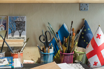 Eclectic artist studio in Tbilisi old town. Art-filled interior with canvases, brushes, handmade signs, posters, framed paintings and creative chaos