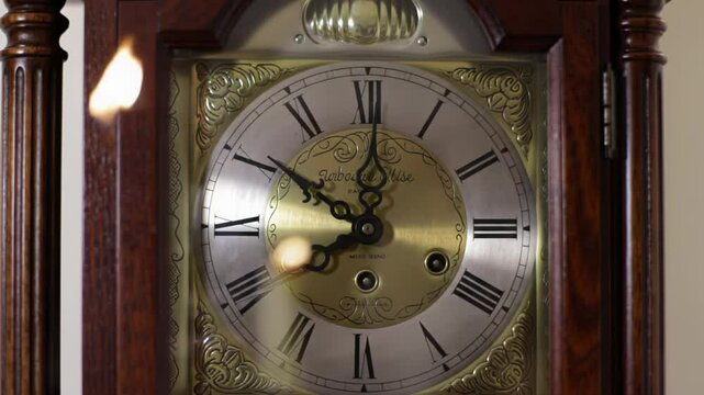Grandfather clock face close up showing golden pendulum movement on antique timepiece. Representing passage time, traditional timekeeping and measurement instrument footage.