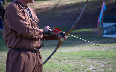 Archer in historical costume aims longbow at a target during a Medieval Fair during a local...