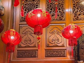 Illuminated red lanterns with gold script at temple. 