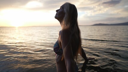 A joyful woman stands in the calm waters of a lake, embracing the serene sunset backdrop of Concepcion Volcano. The warm glow enhances her happiness.